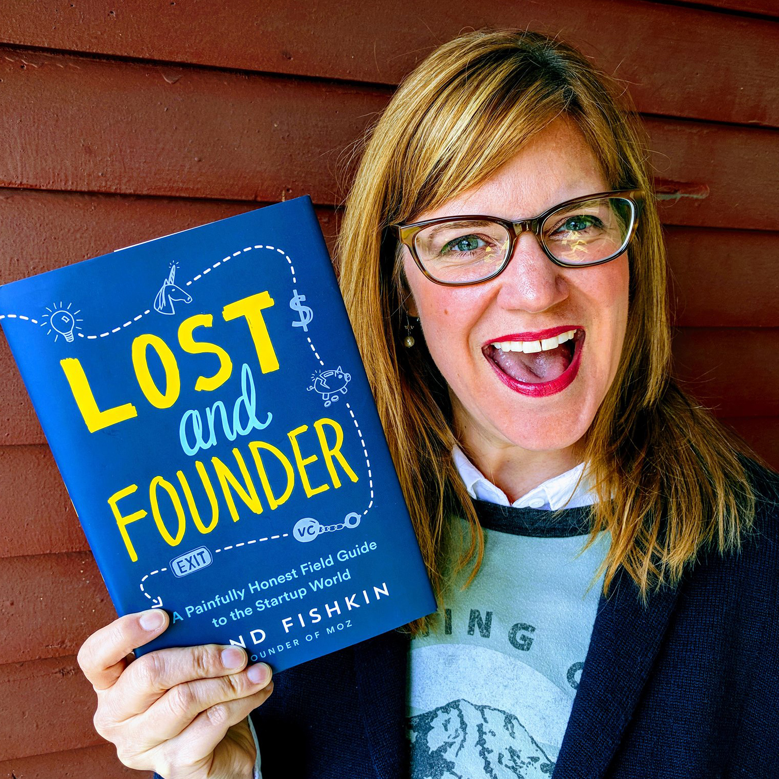 A woman holds a book by her face.